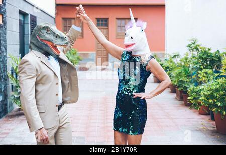 Verrücktes Senioren-Paar tanzt auf der Stadtstraße mit t-rex und Hühnchenmaske - Alte Trend-Leute, die zusammen Spaß haben - Absurdes und lustiges Trend-Konzept Stockfoto