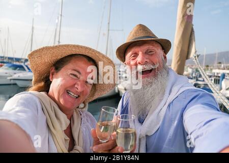 Fröhliches älteres Paar macht selfie, jubelt mit Champagner auf einem segelboot während des Jubiläumsurlaubs - Fröhlicher älterer Lebensstil, Liebe, Reisen und Holid Stockfoto