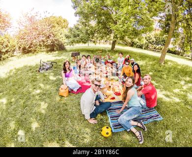 Gruppe glücklicher Freunde, die im Pubblic Park im Freien Picknick machen - Junge Leute trinken Wein und lachen in der Natur - Hauptaugenmerk auf Bottom Guys - Jugend a Stockfoto