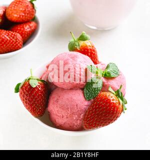 Nahaufnahme der köstlichen Erdbeereishutze mit frischen Erdbeeren in der Schüssel über weißem Steingrund. Leckeres kaltes Sommerdessert. Stockfoto