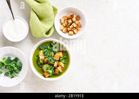 Leckere gesunde Brokkoli grüne Erbsencreme Suppe mit Croutons in der Schüssel über hellem Steingrund mit freiem Textraum. Diätdetox-Food-Konzept. Draufsicht, Stockfoto
