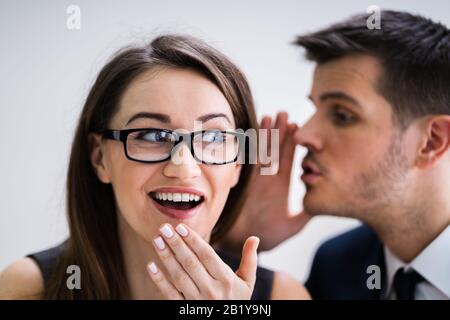 Nahaufnahme Des Geschäftsmannes, der Ins Ohr des weiblichen Partners flüstert Stockfoto