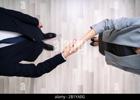 Direkt Über Dem Schuss Von Geschäftsleuten, Die Die Hände Schüttelten, Während Sie Sich Im Büro Auf Dem Fliesen Floor Aufhalten Stockfoto