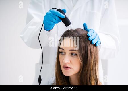 Nahaufnahme der Dermatologe mit Trichoscope für Haarausfall Behandlung seiner Klinik Stockfoto