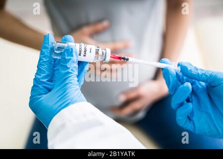 Doctor's Hand halten Sie die Spritze vor der schwangeren Frauen, die Impfung in der Klinik Stockfoto