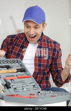 Zufriedener Bauarbeiter mit Werkzeugkasten Stockfoto
