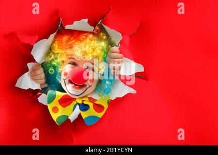 Kind mit Clown Kostüm geht durch EIN Papierloch Stockfoto