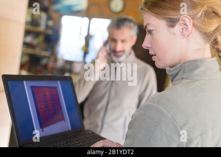 Konzentrierte junge Handwerkerin in der Werkstatt mit Laptop Stockfoto