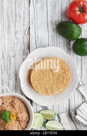 Maistortillas mit gebratenen Bohnen, Avocados, Tomaten und frischen Limes, um vegan tostadas zu machen. Foto von der Draufsicht aufgenommen. Stockfoto