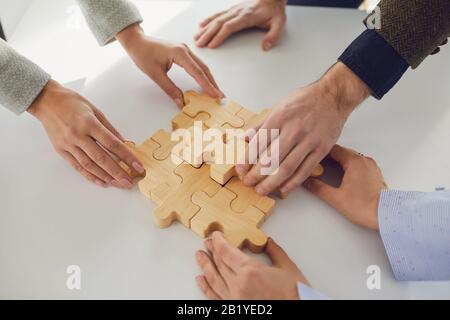 Gesichtslose Geschäftsleute, die Puzzleidee zusammenlegen Stockfoto