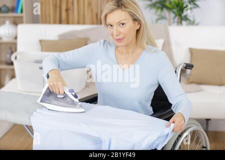 Seniorin im Rollstuhl-Bügelkleider Stockfoto