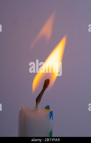 Nahaufnahme einer einzelnen Kerze Flame und Wick auf farbigem Hintergrund Stockfoto