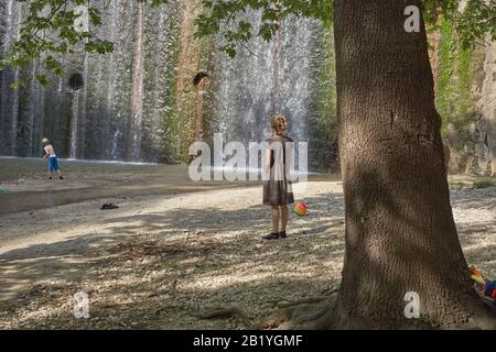 Mutter, die das Kind vor dem Wasserfallurlaub beobachtet, die zusammen gehörende Naturfamilie liebt die Kindheit Stockfoto