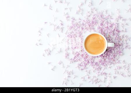 Morgens Frühstück mit Kaffeetasse und lila Blumen auf weißem Hintergrund. Flaches Lay, Draufsicht Frauen Hintergrund. Minimales Konzept, Hochzeit, valentinstag, Stockfoto