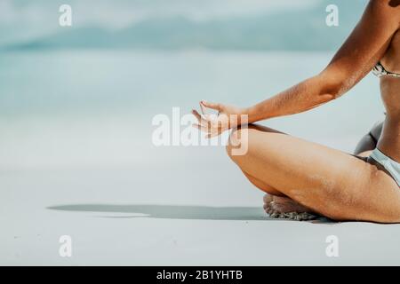 Ernte weiblicher Hände und Beine meditierende Aktivität am Strand Stockfoto
