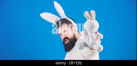 Mann in Plüschanzug mit Hase. Lustige Häschen Mann mit Bart und Schnurrbart. Ostersymbol Konzept. Guy bärtige Hipster niedlich sanfte Hase lange Ohren blauen Hintergrund. Osterhase. Respekt vor Traditionen. Stockfoto