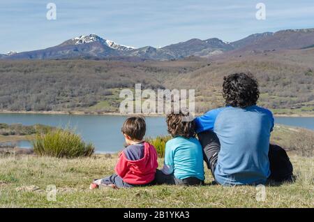 Vater und seine beiden Söhne entspannen sich einen Moment und genießen die Aussicht nach einem harten Wandern in den Bergen Stockfoto