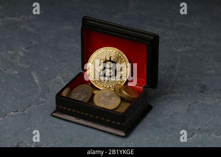 Bitcoin liegt auf rotem Kassettenboden. Kryptokurrency in Form einer Münze Stockfoto