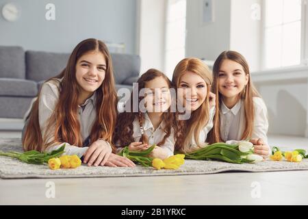 Froher Muttertag. Eine Mutter und drei Töchter, während sie im Zimmer auf dem Boden liegen. Stockfoto