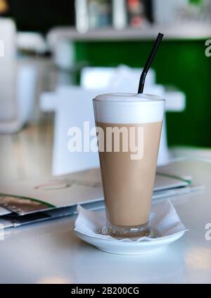 Glas mit Latte auf unscharfem Hintergrund auf dem Tisch im italienischen Café Stockfoto