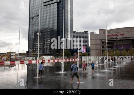 Die Menschen vor Ort interagieren mit den neuen Springbrunnen auf dem Centenary Square in Birmingham, Großbritannien. Die 16-£-Neubebauung des "Birminghams Centenary Square" wurde nun offiziell eröffnet. Paradise, früher Paradise Circus genannt, ist die Bezeichnung für eine Fläche von rund 7 Hektar im Stadtzentrum von Birmingham zwischen Chamberlain und Centenary Squares. Das Gebiet gehört seit dem 19. Jahrhundert zum Bürgerzentrum von Birmingham. Ab 2015 wird die Argent Group das Gebiet zu neuen Gebäuden mit gemischter Nutzung und öffentlichen Plätzen umbauen. Stockfoto