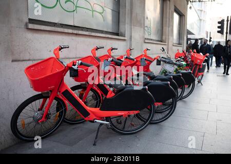 Row of Standing Jump Dockless Bike-Sharing Electric Cycles am 21. Januar 2020 in London, England, Großbritannien. Social Bikes Inc., die als Jump firmiert, ist ein Dockless Roller und ein elektrisches Fahrradteilungssystem, das in den Vereinigten Staaten, Deutschland, Portugal und Großbritannien betrieben wird. Die Fahrräder sind leuchtend rot orange. Sie können über die Jump- oder Uber-Apps gefunden werden, und Benutzer werden ihrem Uber-Konto belastet. Stockfoto