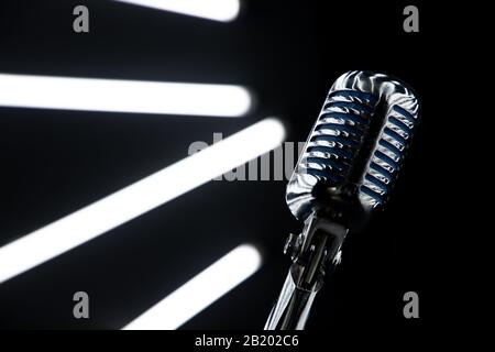 Verlieren Sie das Mikrofon in Music Studio mit schwarzen Wänden und Lichtern im Hintergrund Stockfoto