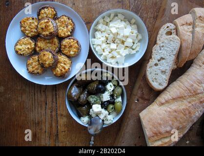 Tisch mit verschiedenen vegetarischen Speisen mit gefüllten Champignons, Oliven, gefüllten Weinblättern, Brot und Fetakäse Stockfoto