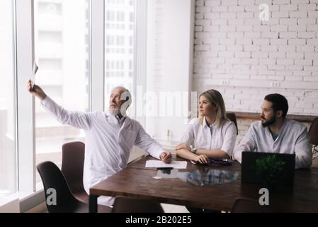 Der Chefarzt der Krankenhausabteilung erklärt seinen Kollegen das Ergebnis Stockfoto