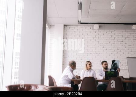 Das medizinische Team von drei erwachsenen und jungen Ärzten diskutiert Röntgenaufnahmen der Brust Stockfoto