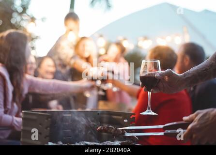 Fröhliche Familie, die auf der Grillparty festlichen Toast macht - Junge und ältere Eltern haben Spaß beim gemeinsamen Essen im Garten Stockfoto