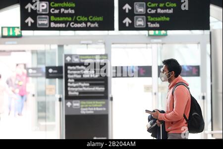 Ein Mann, der in der Ankunftshalle von Terminal 2 am Flughafen Dublin eine Gesichtsmaske trägt. Stockfoto