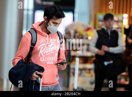 Ein Mann, der in der Ankunftshalle von Terminal 2 am Flughafen Dublin eine Gesichtsmaske trägt. Stockfoto