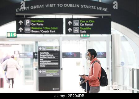 Ein Mann, der in der Ankunftshalle von Terminal 2 am Flughafen Dublin eine Gesichtsmaske trägt. Stockfoto