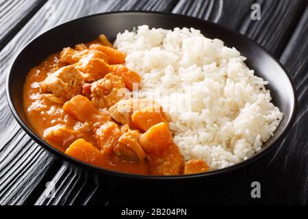 Afrikanischer Eintopf Domoda mit Erdnüssen, gekocht mit Hühnerkürbis, serviert mit Reis aus nächster Nähe in einem Teller auf dem Tisch. Horizontal. Stockfoto