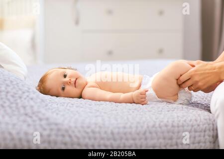 Die Hände der Mutter halten das Baby an den Beinen. Stockfoto