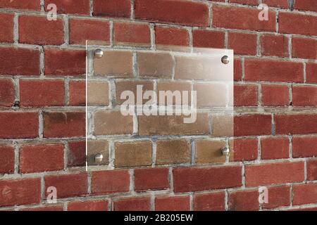 Leere horizontale transparente Glasschilder an der roten Ziegelwand. Typenschild mit Beschneidungspfad um das Glas. Seitenansicht Stockfoto