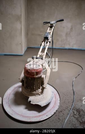 Professionelle Maschine zum Aufführen und Polieren von Sand und Zement Estrichboden auf der Baustelle einer neuen zweistöckigen Wohnung. Sand und Zement Stockfoto