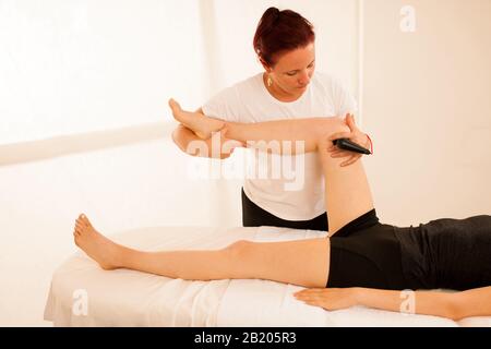 Physiotherapeut, der Tecar-Therapie-Alterantiva-Behandlung bei einem Frauen-Patienten macht Stockfoto