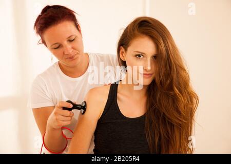 Physiotherapeut, der Tecar-Therapie-Alterantiva-Behandlung bei einem Frauen-Patienten macht Stockfoto