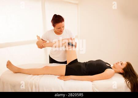 Physiotherapeut, der Tecar-Therapie-Alterantiva-Behandlung bei einem Frauen-Patienten macht Stockfoto