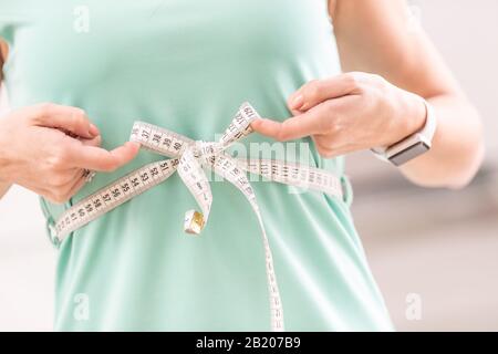 Gewichtsverlust und schlanker Körper einer jungen Frau. Mädchen misst ihren Taillenkörper mit Maßband. Stockfoto