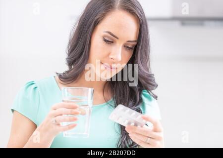 Schöne junge Frau, die Blisterpackung mit Pillen hält und medizinische Anweisungen liest. Stockfoto