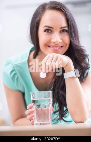 Junge Frau mit Magnesia Efferveszenztablette und Glas reinem oder Mineralwasser. Stockfoto