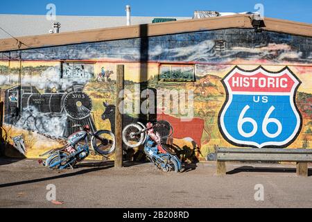 Außenansicht des Kupferwagens, Seligman, Arizona, USA. Historisches Route 66 Schild und malerisches Wandgemälde mit Motorrädern in Beton Stockfoto