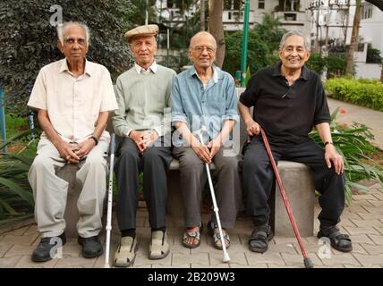 Bengaluru, INDIEN - 25. Juni 2010. Eine Gruppe alter indischer Senioren entspannen sich auf einer Parkbank in Bangalore, Indien Stockfoto
