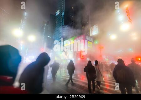 Der treibende Dampf umgibt die Gebäude People, Traffic und Times Square in der verschneiten Nacht in Midtown Manhattan New York City, New York, New York, New York, USA, am Jan. 2020. Stockfoto