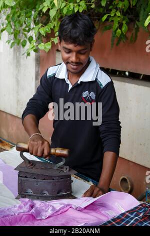 Bengaluru, INDIEN - 24. Oktober 2012. Indianischer Mann bügelt im Freien mit einem Kohlekasten-Eisen, Bengaluru (Bangalore), Indien Stockfoto
