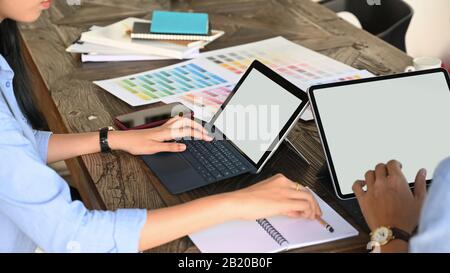 Zugeschnittenes Bild des Grafikdesigner-Teams, das über Farbe für ihr neues Projekt am Holztisch spricht. Stockfoto