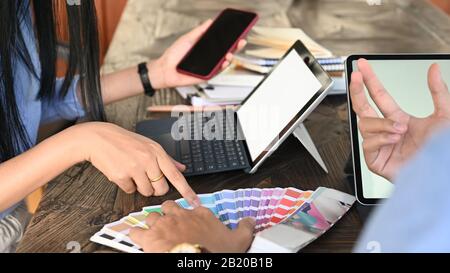 Zugeschnittenes Bild des Grafikdesigner-Teams, das über Farbe für ihr neues Projekt am Holztisch spricht. Stockfoto